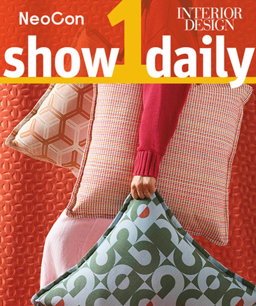 Person in a red sweater holds three patterned pillows in front of a red textured background, with "NeoCon show daily" and "Interior Design" text overlaid at the top.