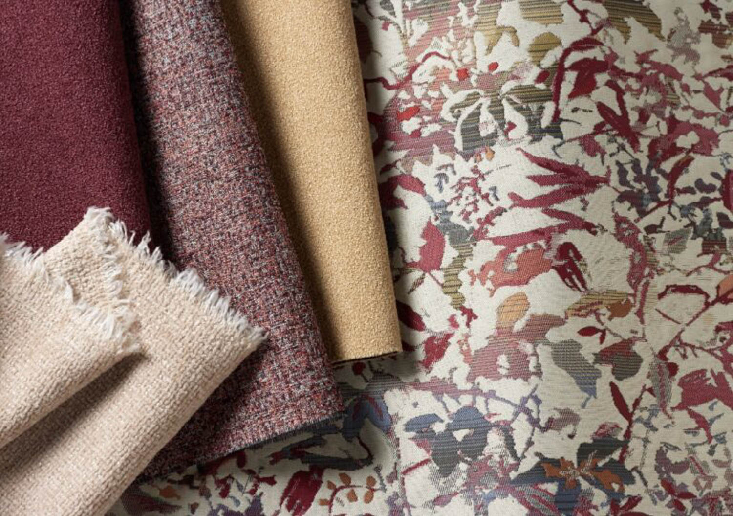 A selection of fabric samples, including solid, textured, and multi-colored floral patterns, arranged side by side on a flat surface.