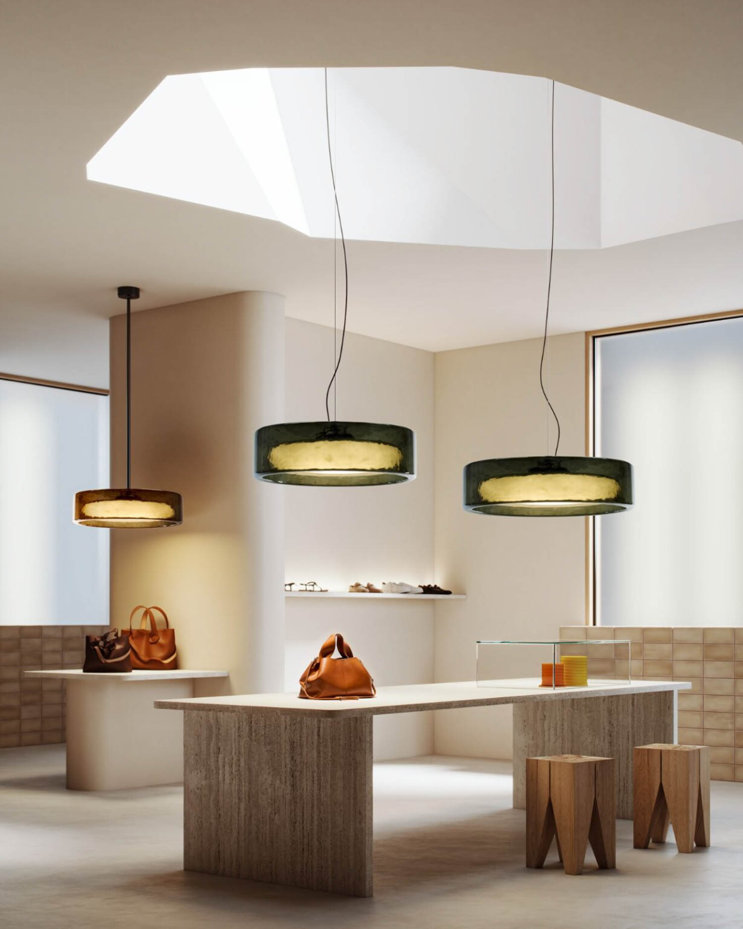Modern retail store interior with three pendant lights, a wooden table displaying handbags, wooden stools, and shelves with accessories, all under a large skylight.