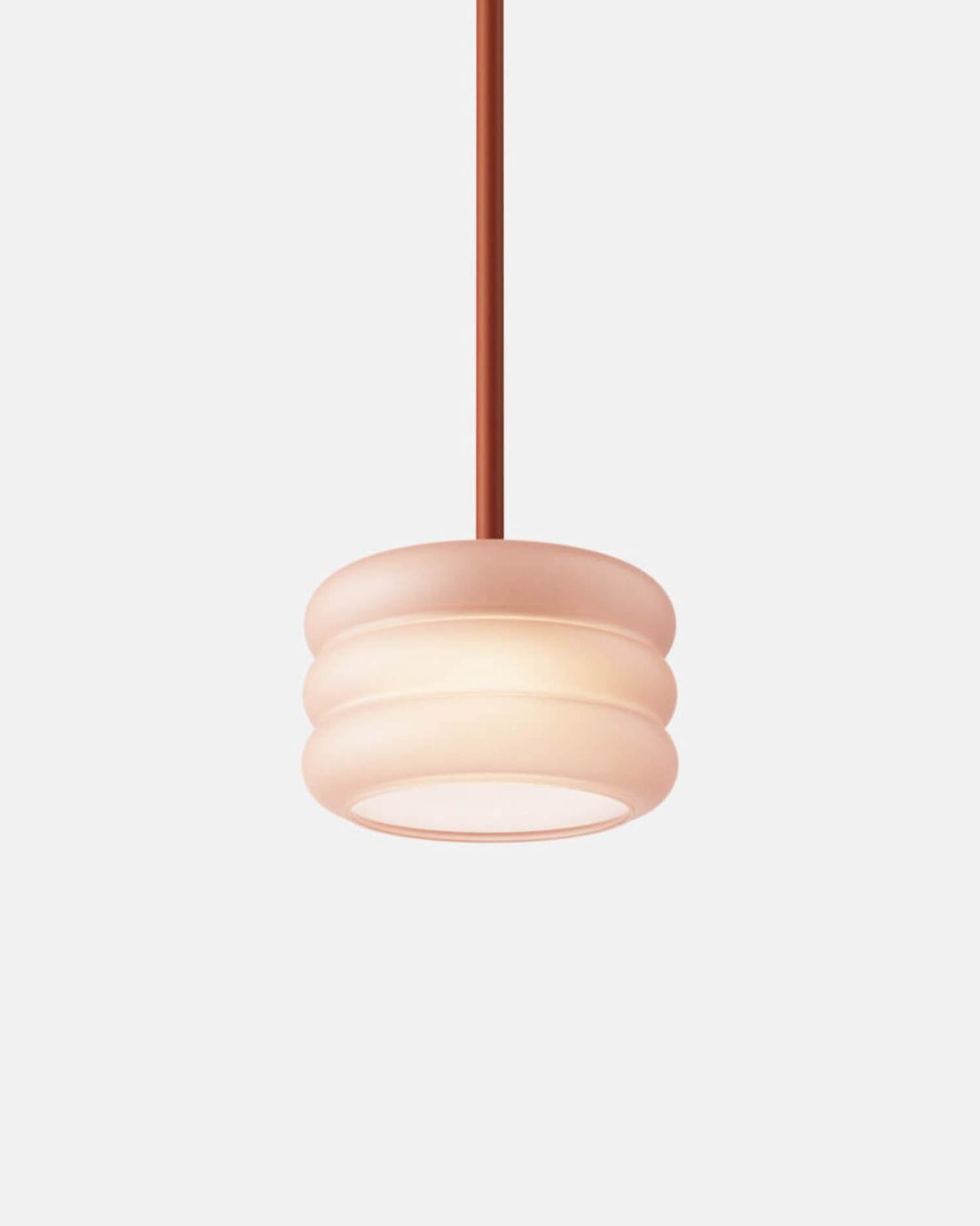 A modern pendant light with a ribbed, frosted glass shade and a straight, reddish-brown cord against a plain white background.