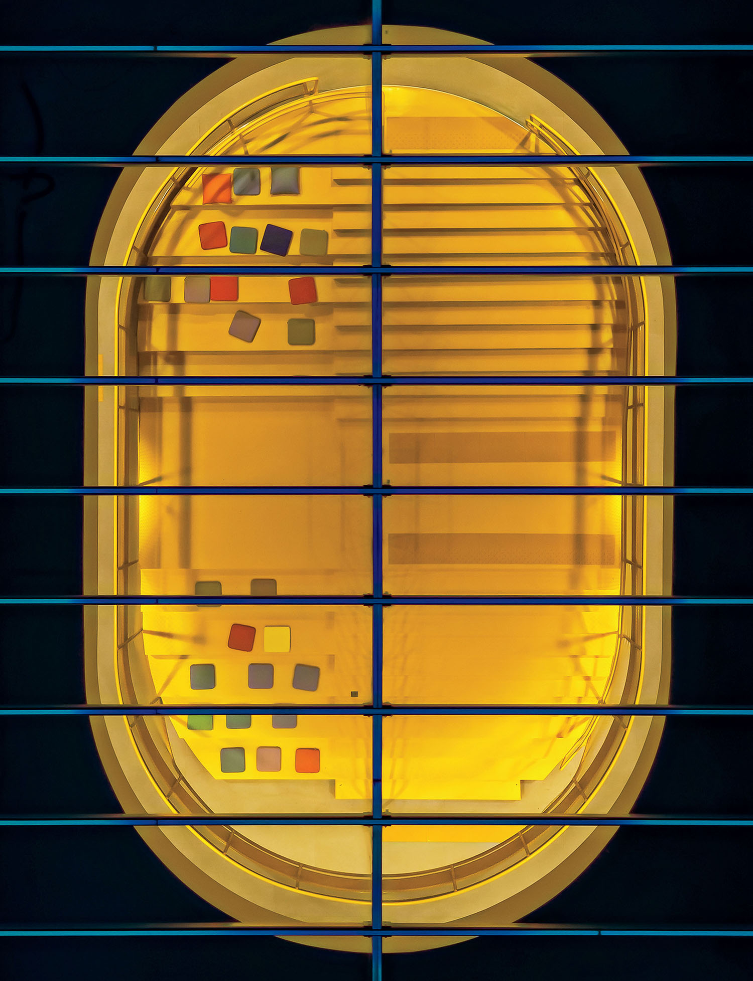 Oval-shaped yellow-lit window seen through horizontal metal bars, with colorful square stickers on the glass and stairs visible inside.
