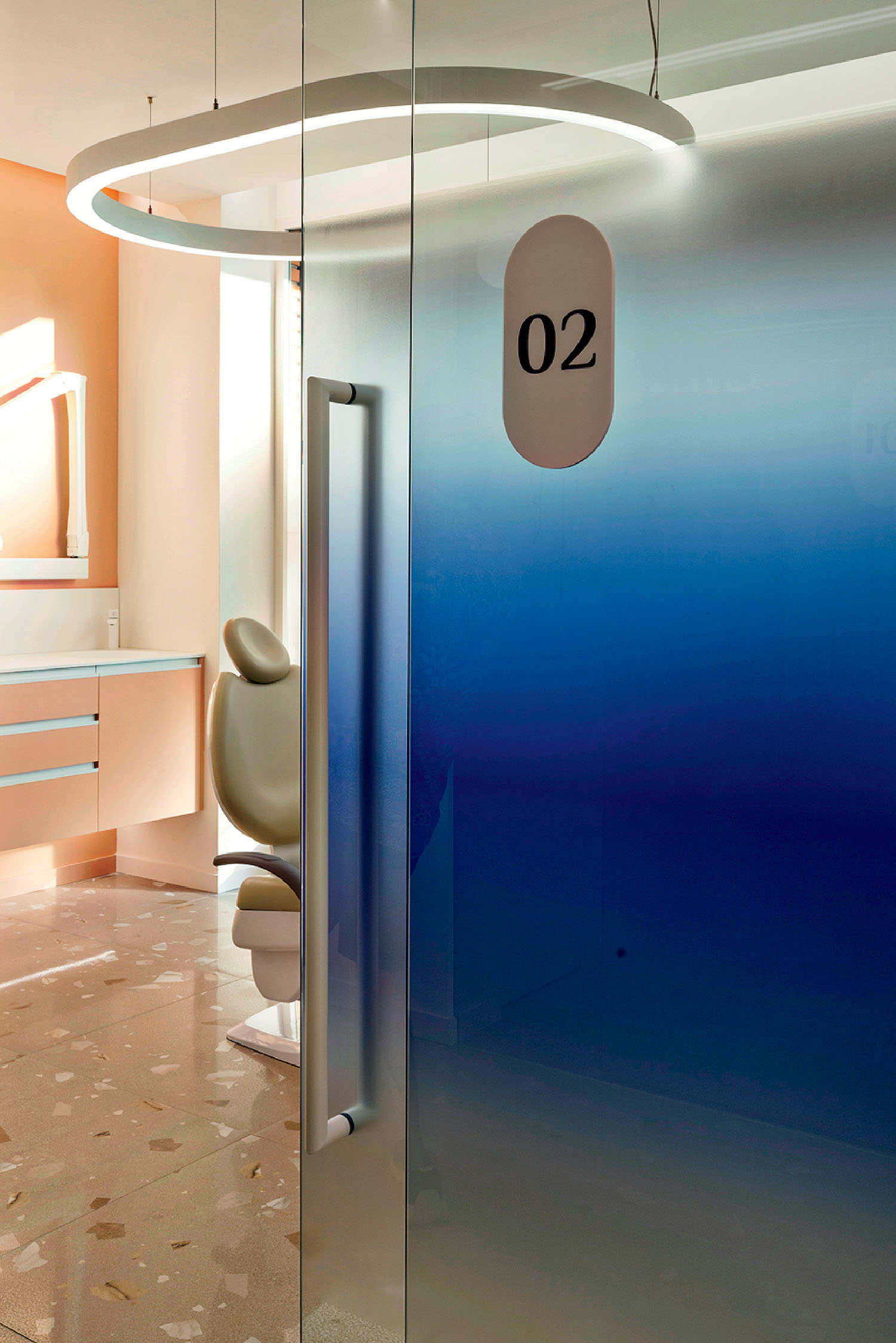 A modern dental clinic room with a blue gradient glass door labeled "02," a dental chair, and a round ceiling light.