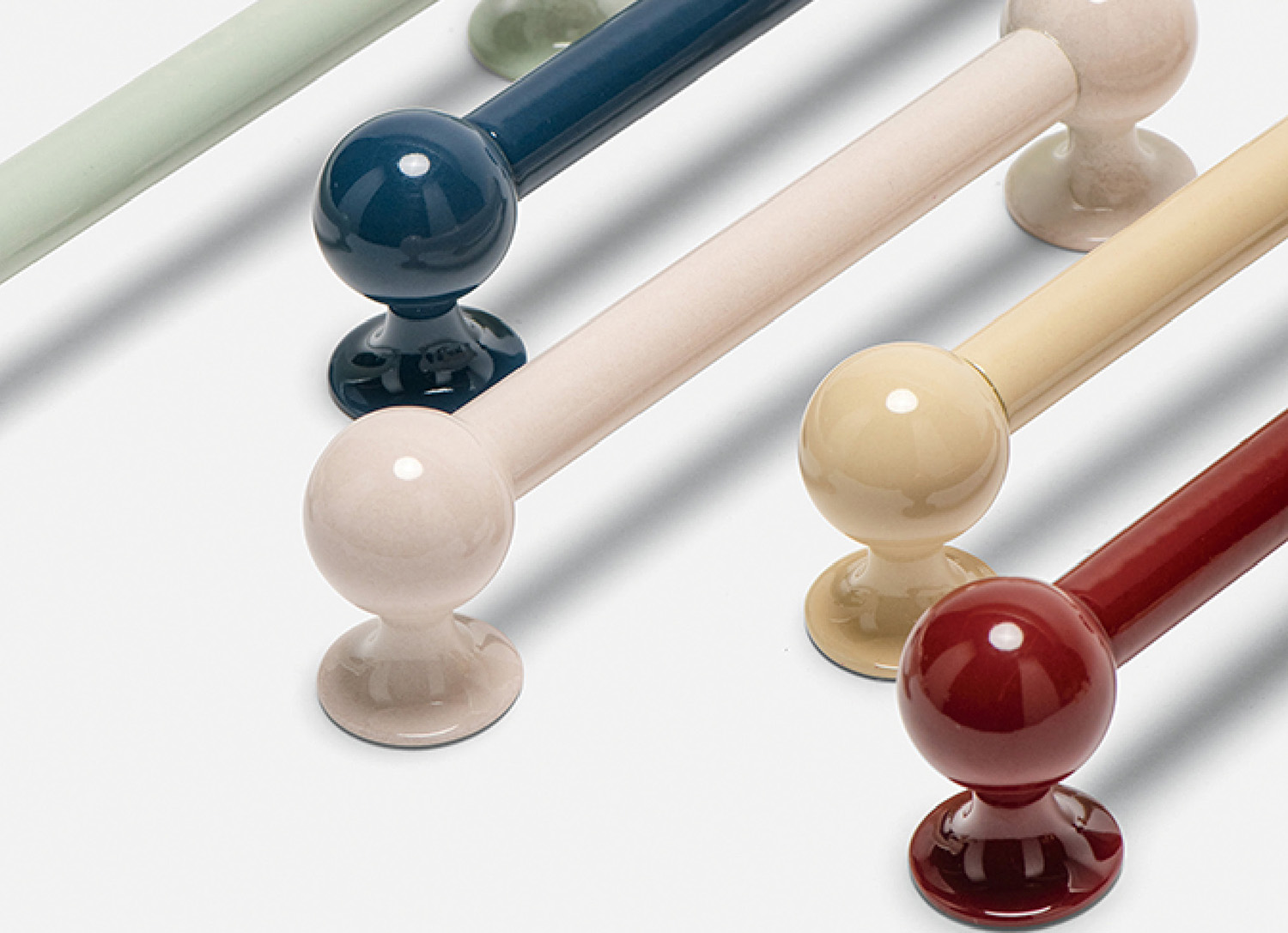 Five glossy, spherical-ended bars in pastel and primary colors arranged diagonally on a white surface.
