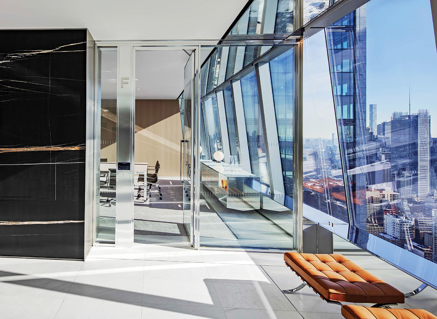 Modern office with floor-to-ceiling windows, a glass-walled conference room, marble and leather accents, and a city skyline view.