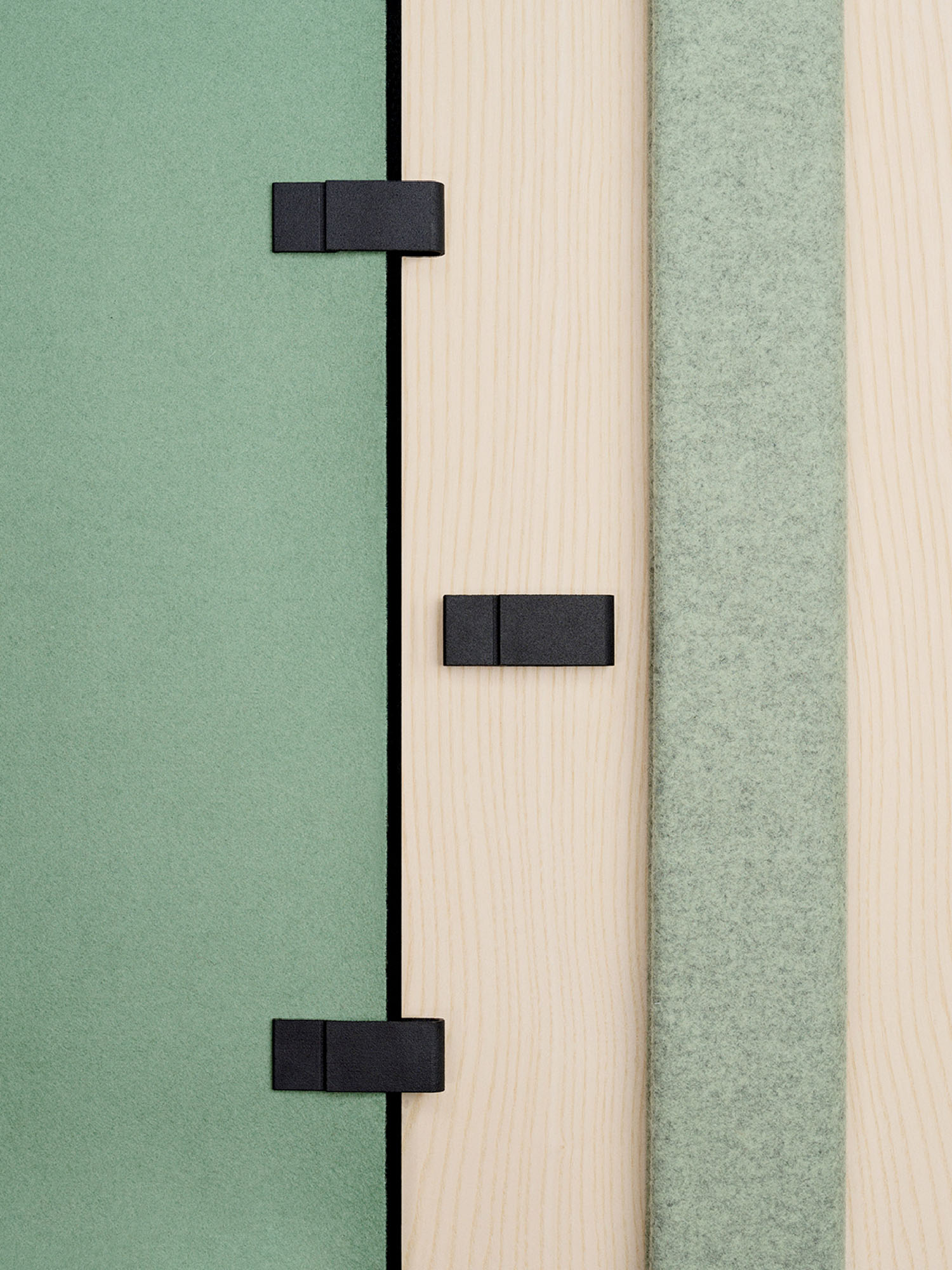 A close-up of geometric panels in green and beige tones with black rectangular clips attached at intervals.