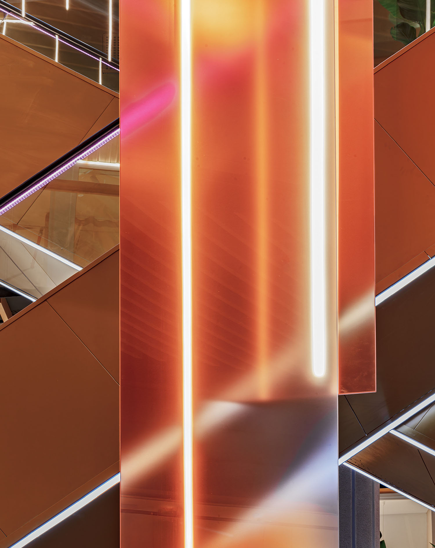 Close-up of an architectural interior featuring reflective copper panels, white vertical light strips, and intersecting diagonal lines.
