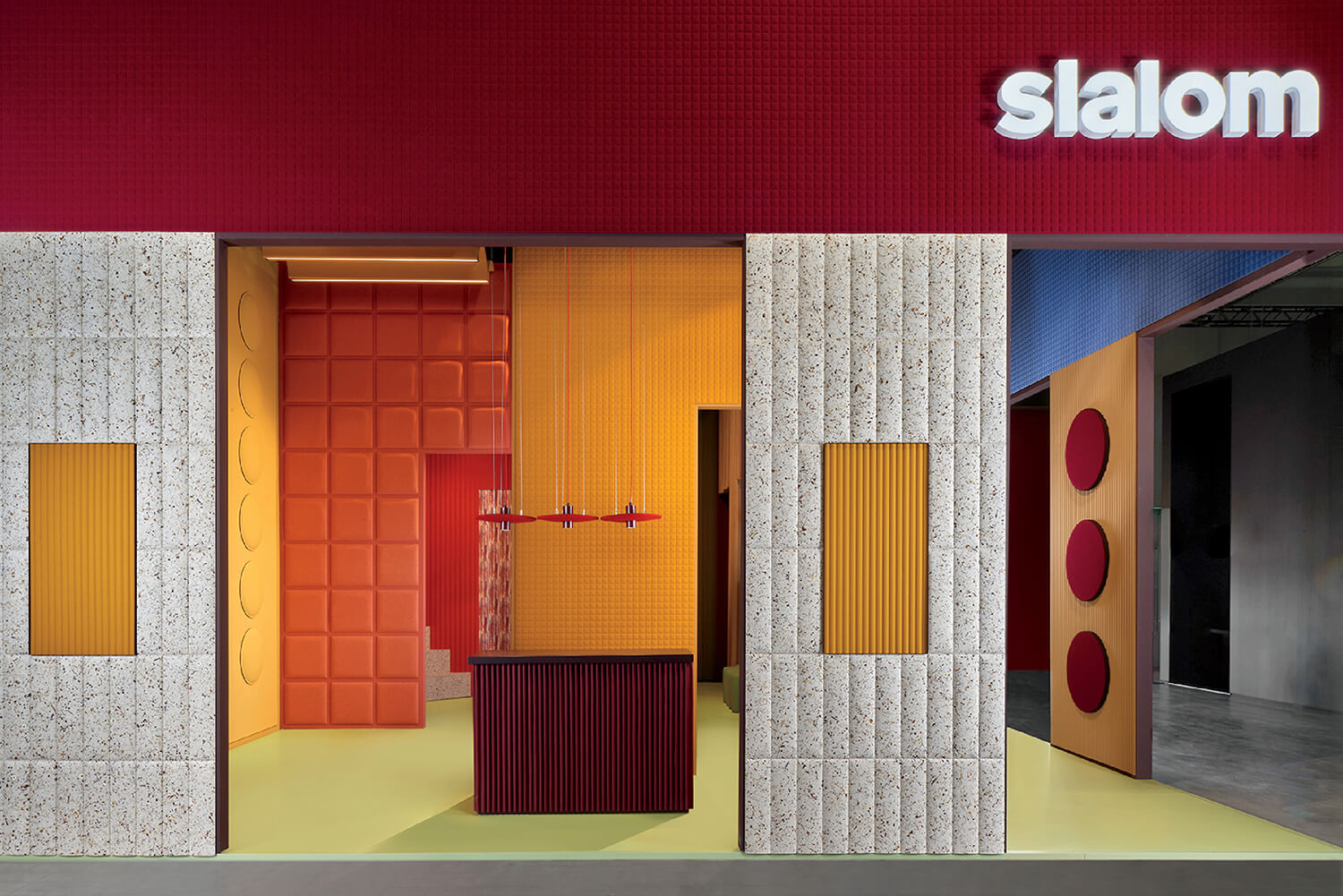 Modern storefront with bold geometric patterns and colors, featuring red, yellow, and orange panels, textured walls, and "slalom" signage in white letters.