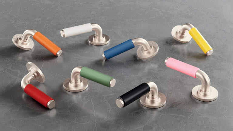 Eight silver door handles with cylindrical grips in different colors—orange, white, blue, yellow, red, green, black, and pink—are arranged on a gray marble surface.