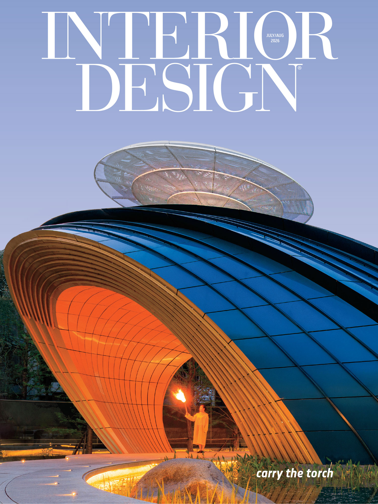 A modern, curved building with glowing orange interior lighting and a person holding a torch, featured on the cover of Interior Design magazine.