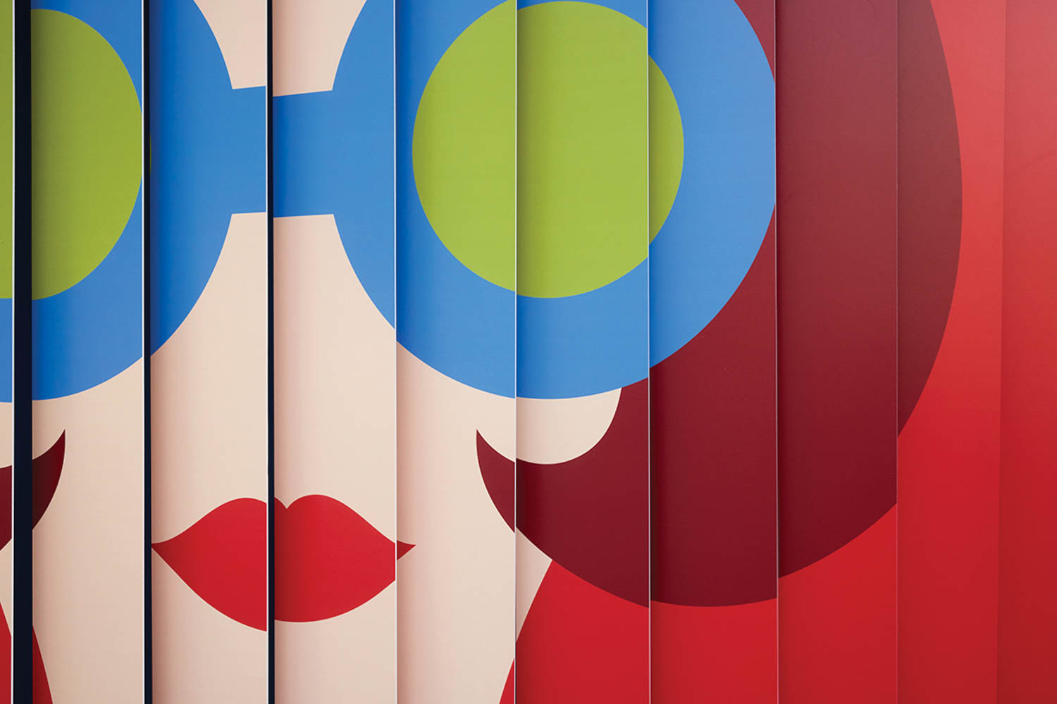 Abstract illustration of a face with blue round glasses, green lenses, red lips, and red hair, created on vertical panels.