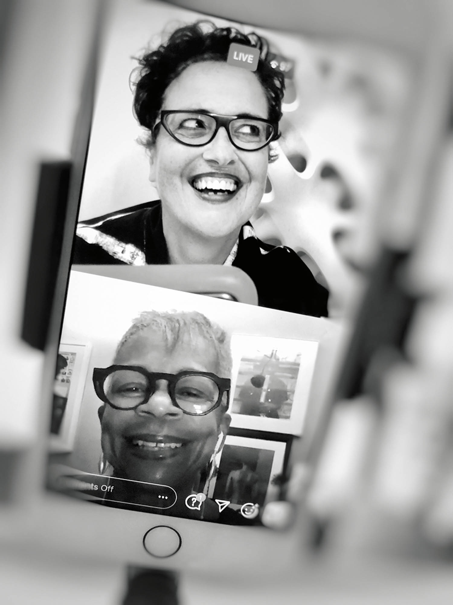Two people smiling during a video call, shown on a smartphone screen in black and white.