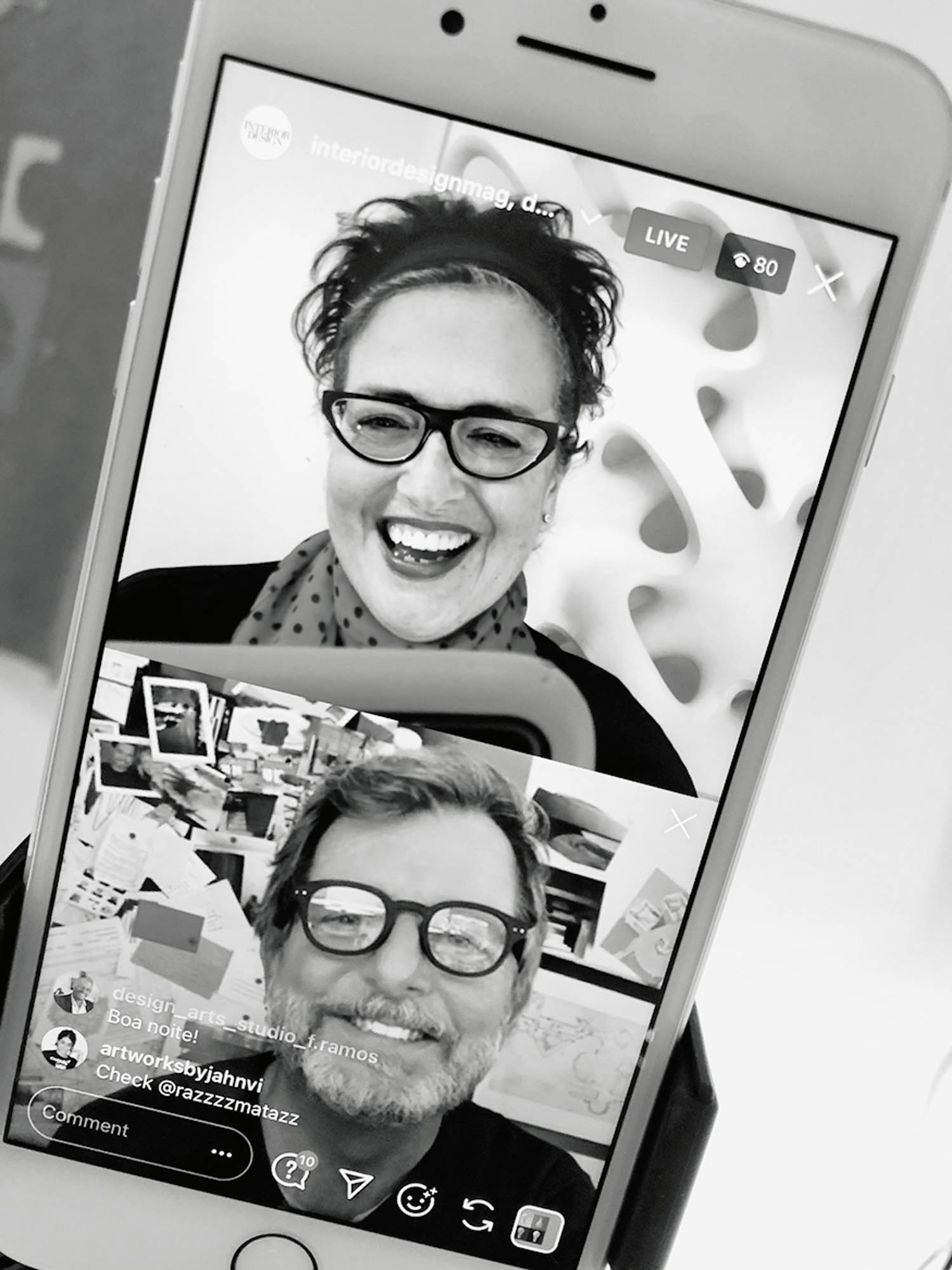 Black-and-white photo of a phone screen showing two people on a video call, both wearing glasses and smiling; live viewer count is 80.
