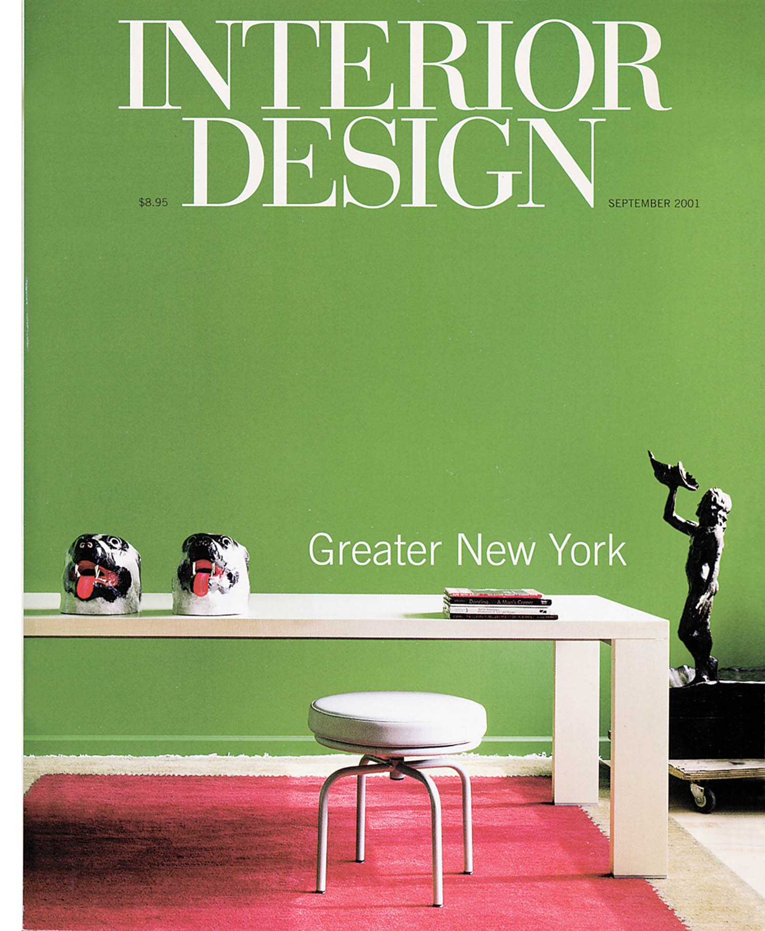Magazine cover titled “Interior Design” features a white table, two decorative heads, a white stool, a sculpture, and a red rug against a green wall. Text reads “Greater New York.”.