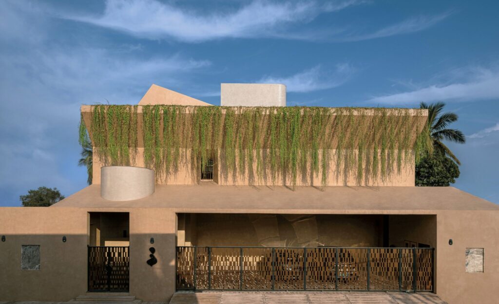 Modern beige building with geometric shapes, metal gate, and long green vines hanging from the roof, set against a blue sky with scattered clouds.