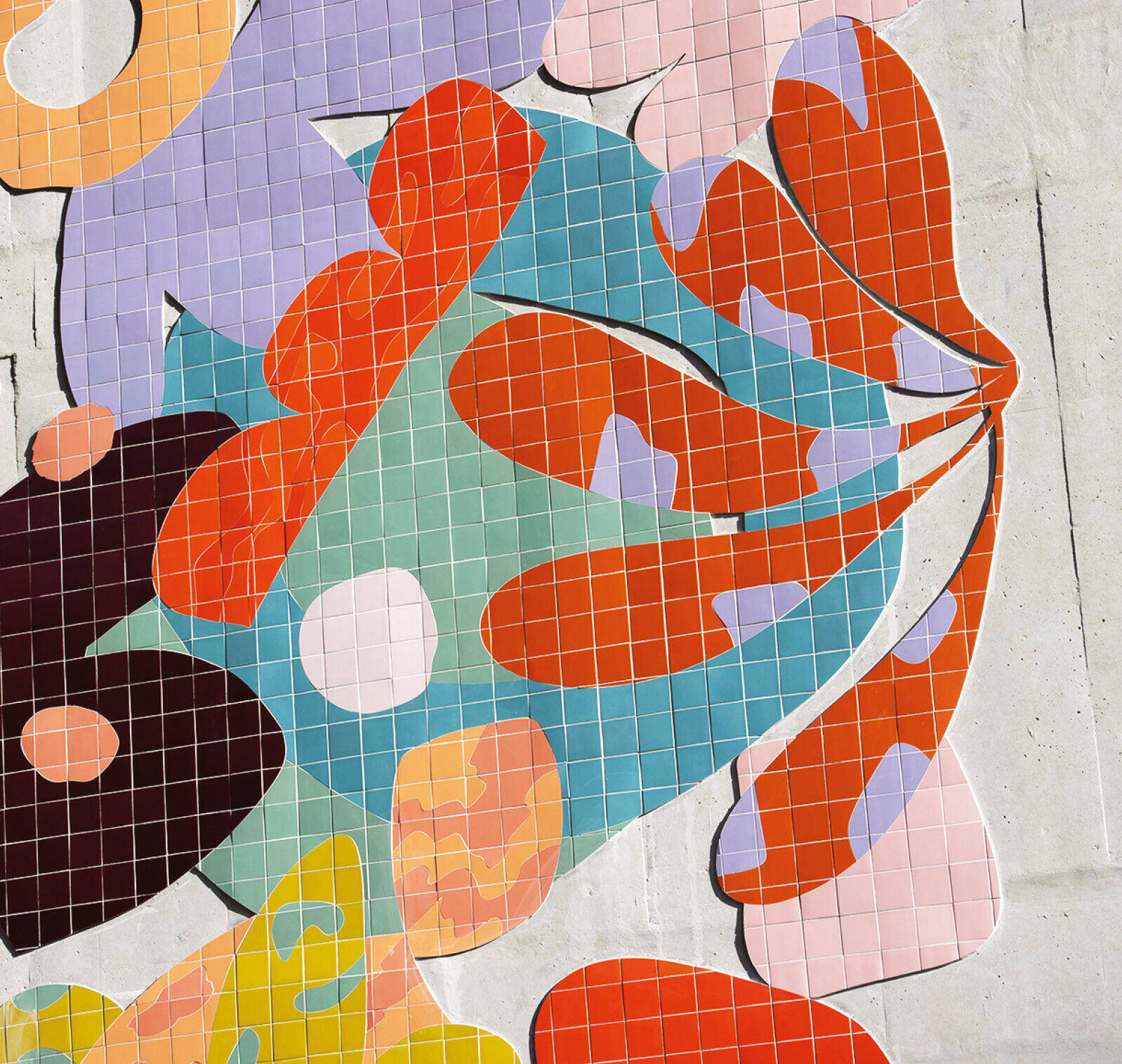 Colorful abstract tile mosaic with overlapping shapes in red, orange, pink, green, blue, and black on a light gray wall.