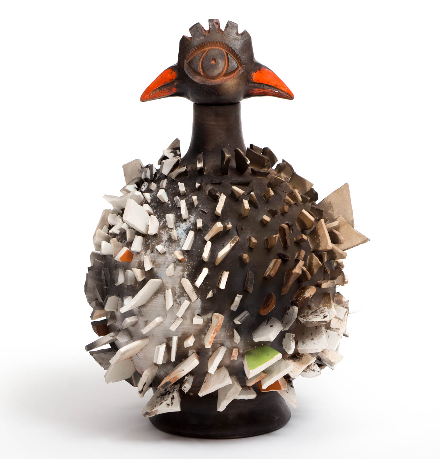 Ceramic bird sculpture with a spiky body, an eye on its head, and orange beak and ear-like shapes, against a white background.