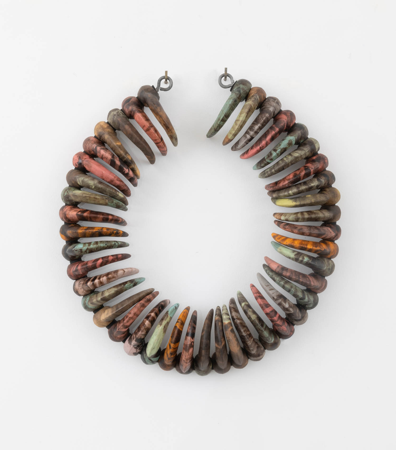 A circular necklace made of pointed, multicolored beads in earthy tones, arranged closely together with metal clasps at the ends, displayed on a white background.