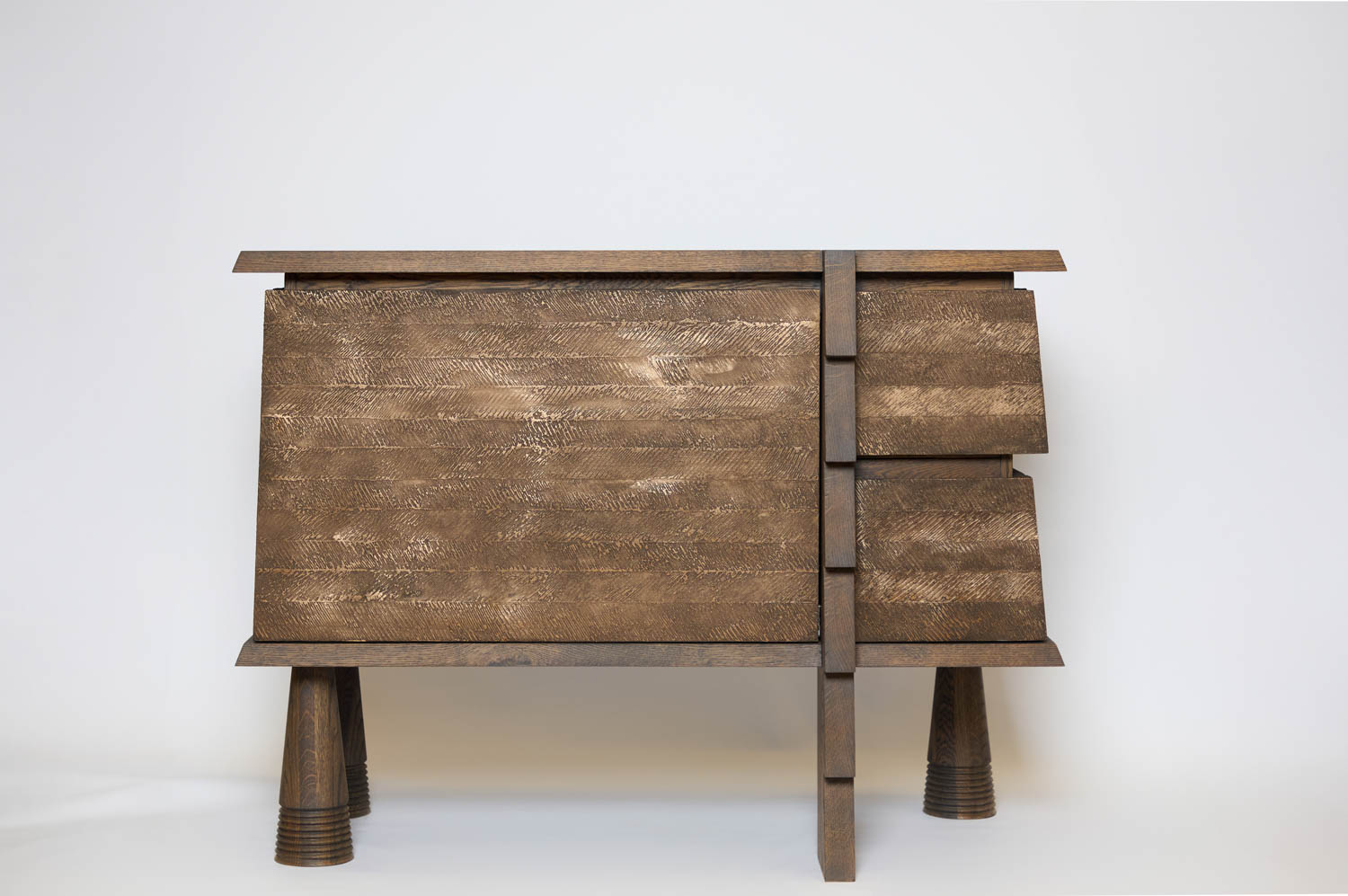 Wooden sideboard with a textured finish, two left-facing doors, two right drawers, four cylindrical legs, and a vertical central divider, pictured against a plain white background.