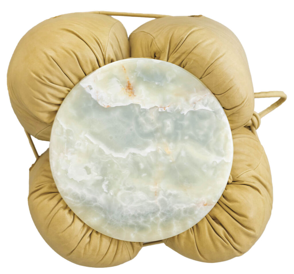 Round marble tabletop on a cushion-like, tan leather base viewed from above; four distinct, padded leather sections form the support structure.