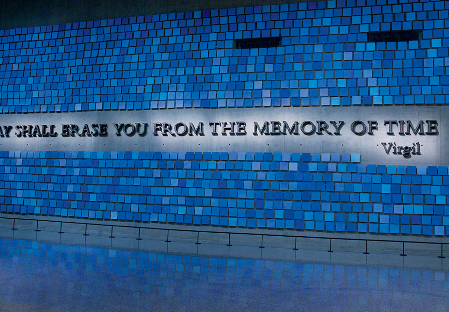A wall of blue tiles with the words “NO DAY SHALL ERASE YOU FROM THE MEMORY OF TIME – Virgil” displayed at the center.