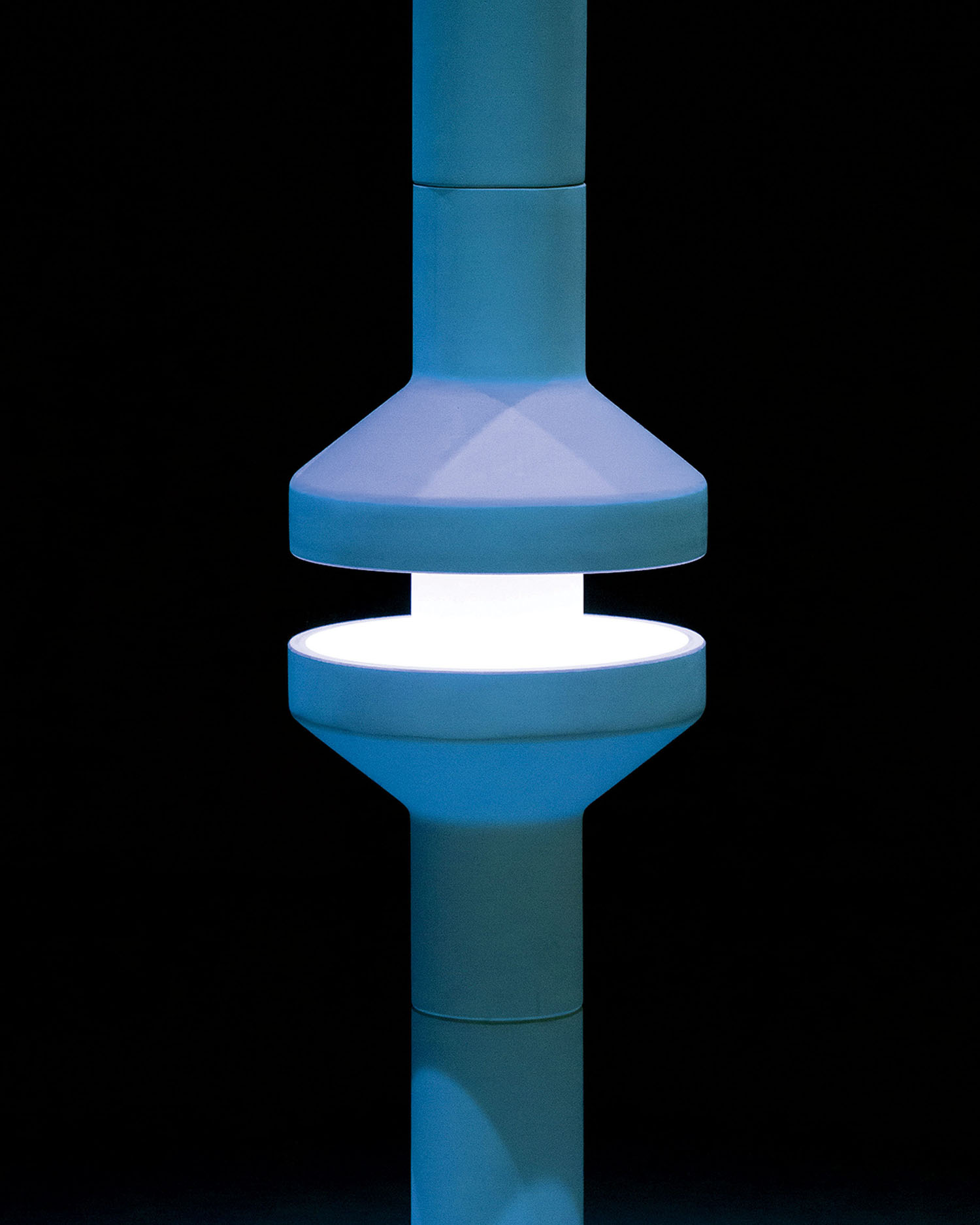 A cylindrical blue and white light fixture is segmented in the middle, emitting a bright white glow against a black background.