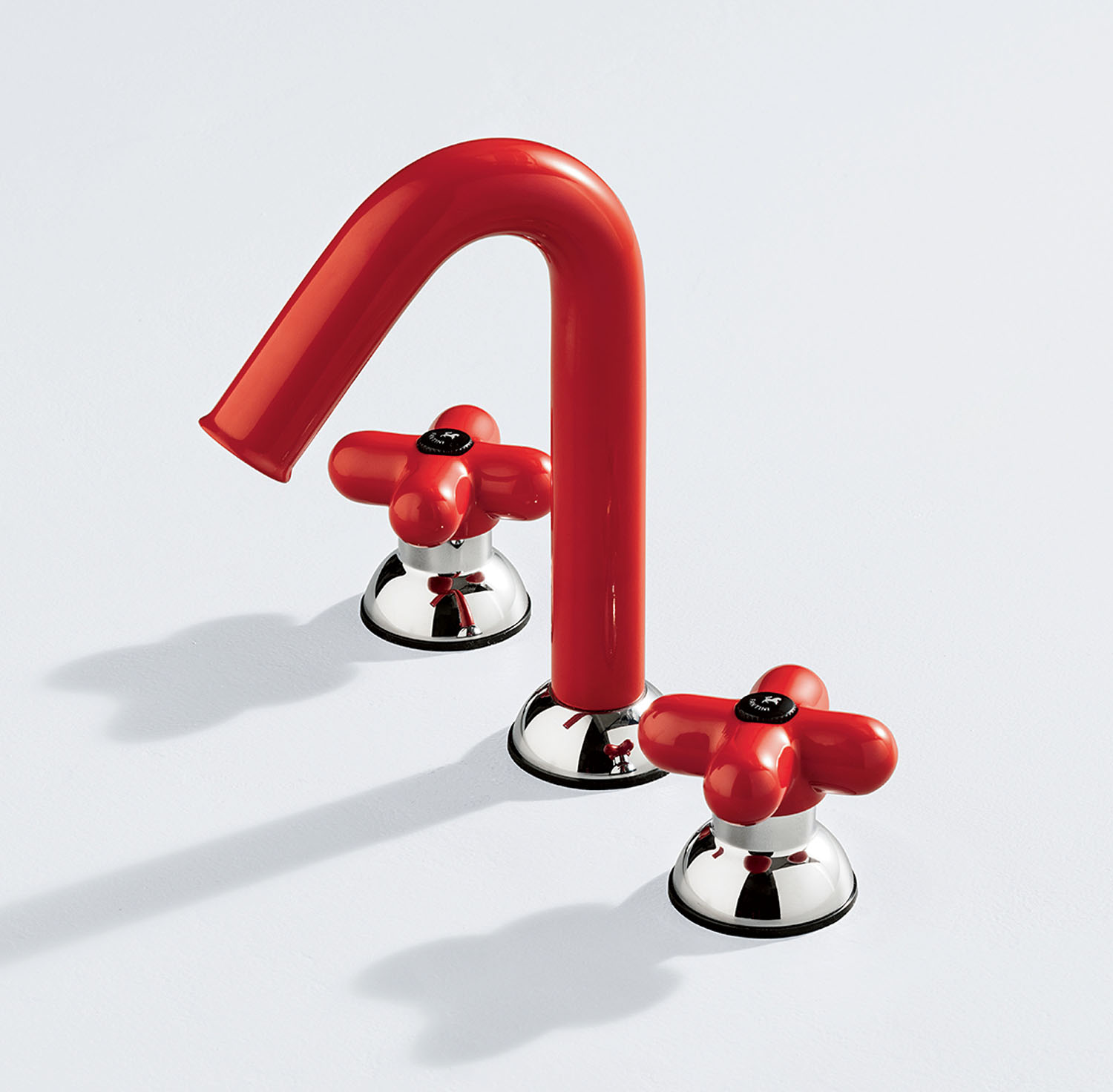 A red faucet with matching hot and cold knobs on a white surface. The handles and spout have a glossy finish with chrome bases.