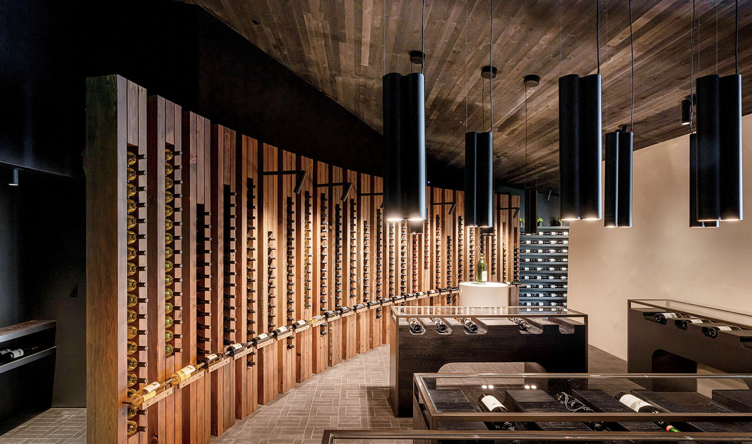 Modern wine cellar with bottles stored horizontally on wall-mounted racks and glass display cases.