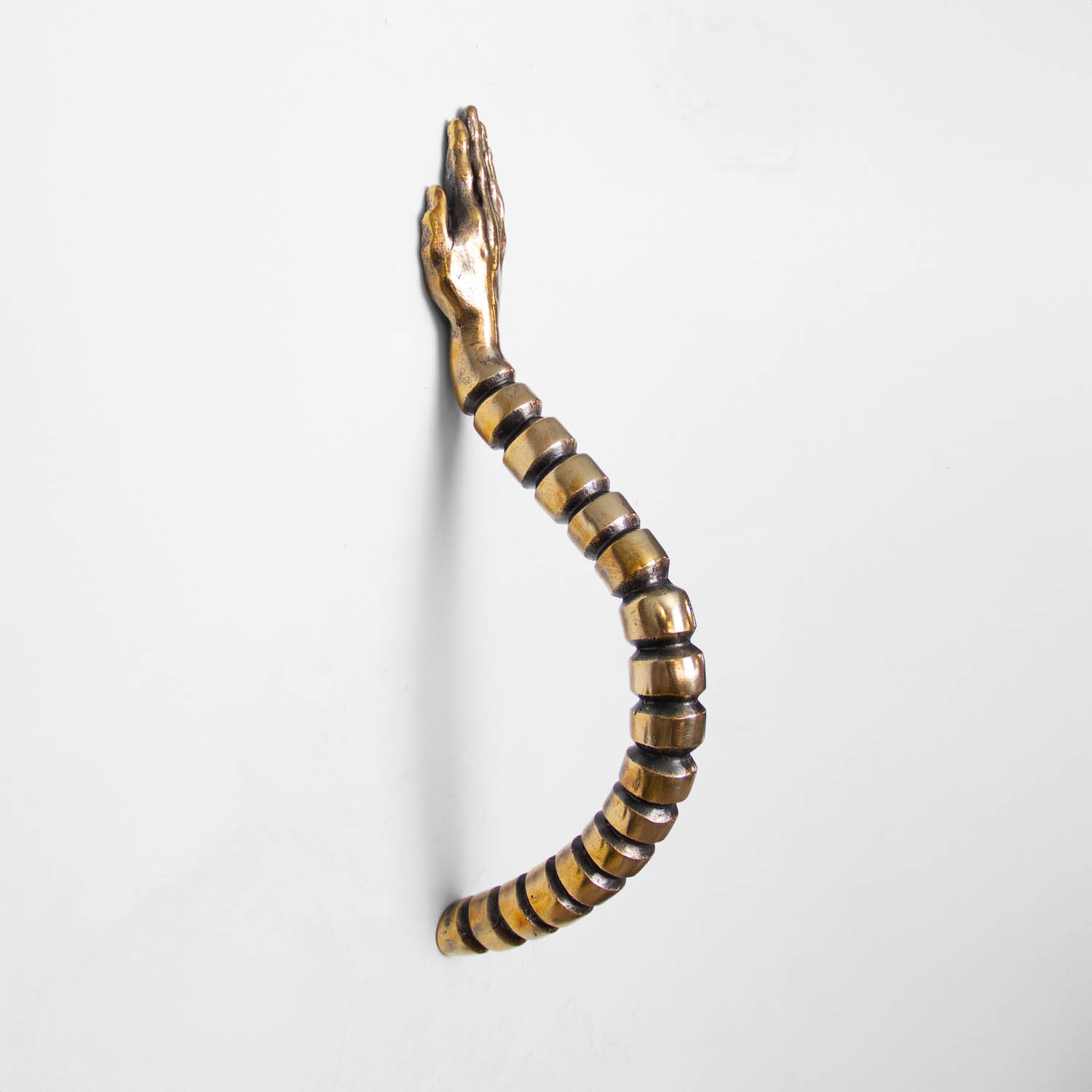 A brass door handle shaped like a segmented spinal column topped with an open hand.