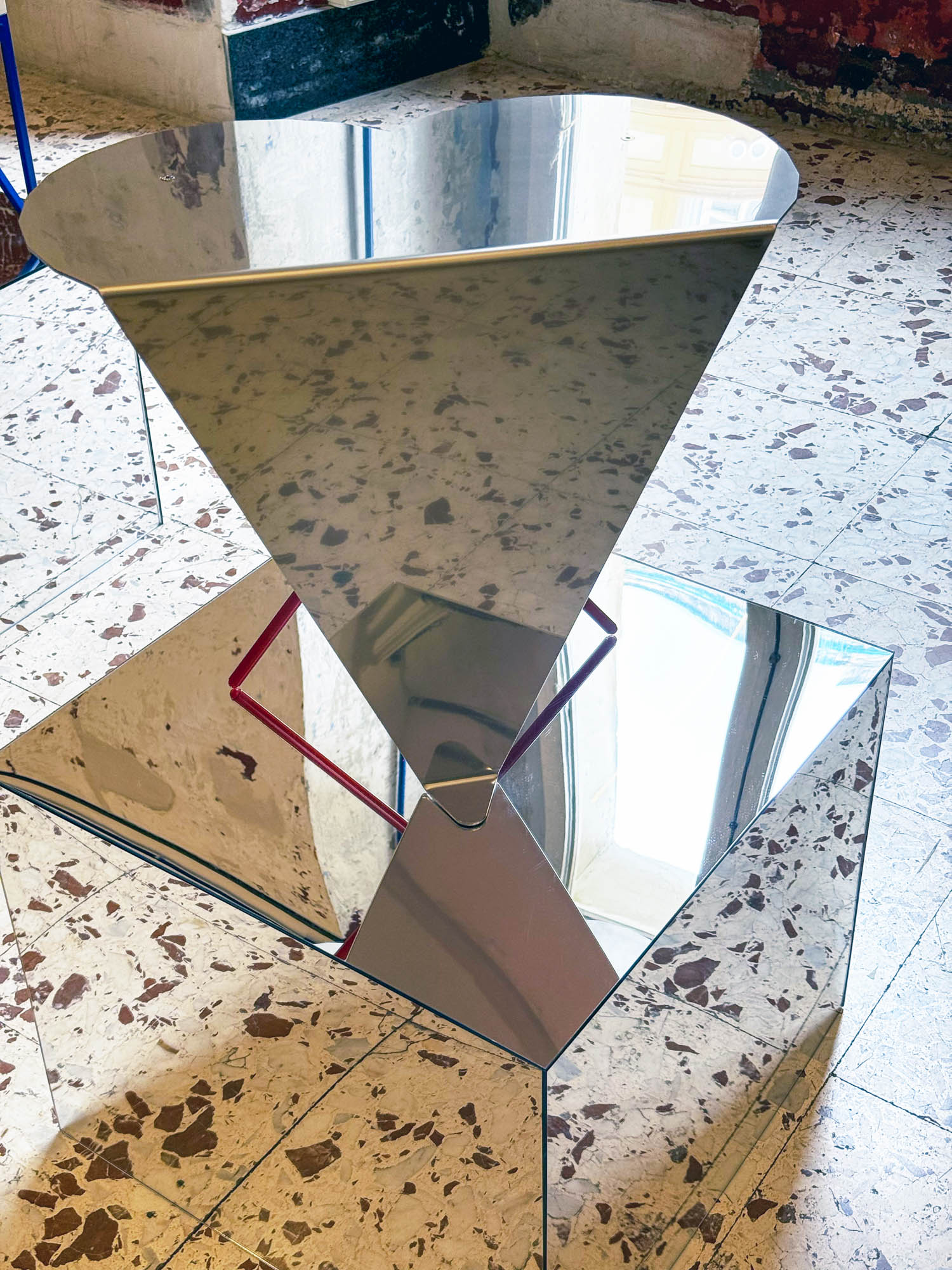 A mirrored, inverted pyramid resting on a mirrored cube base.