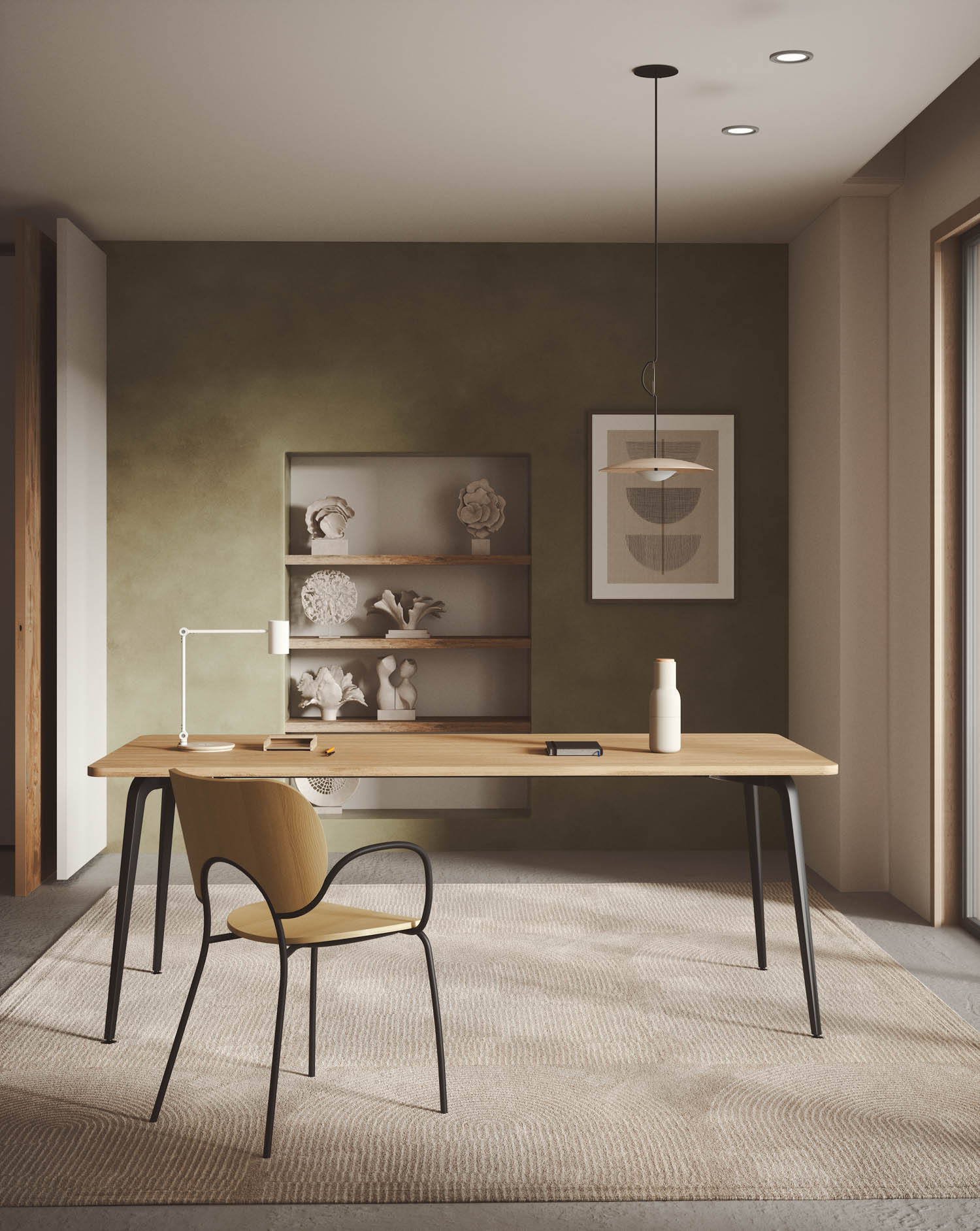 Minimalist home office with a wooden desk, beige chair, desk lamp, and decor items on shelves against a green accent wall. Framed art and a pendant light complete the modern space.