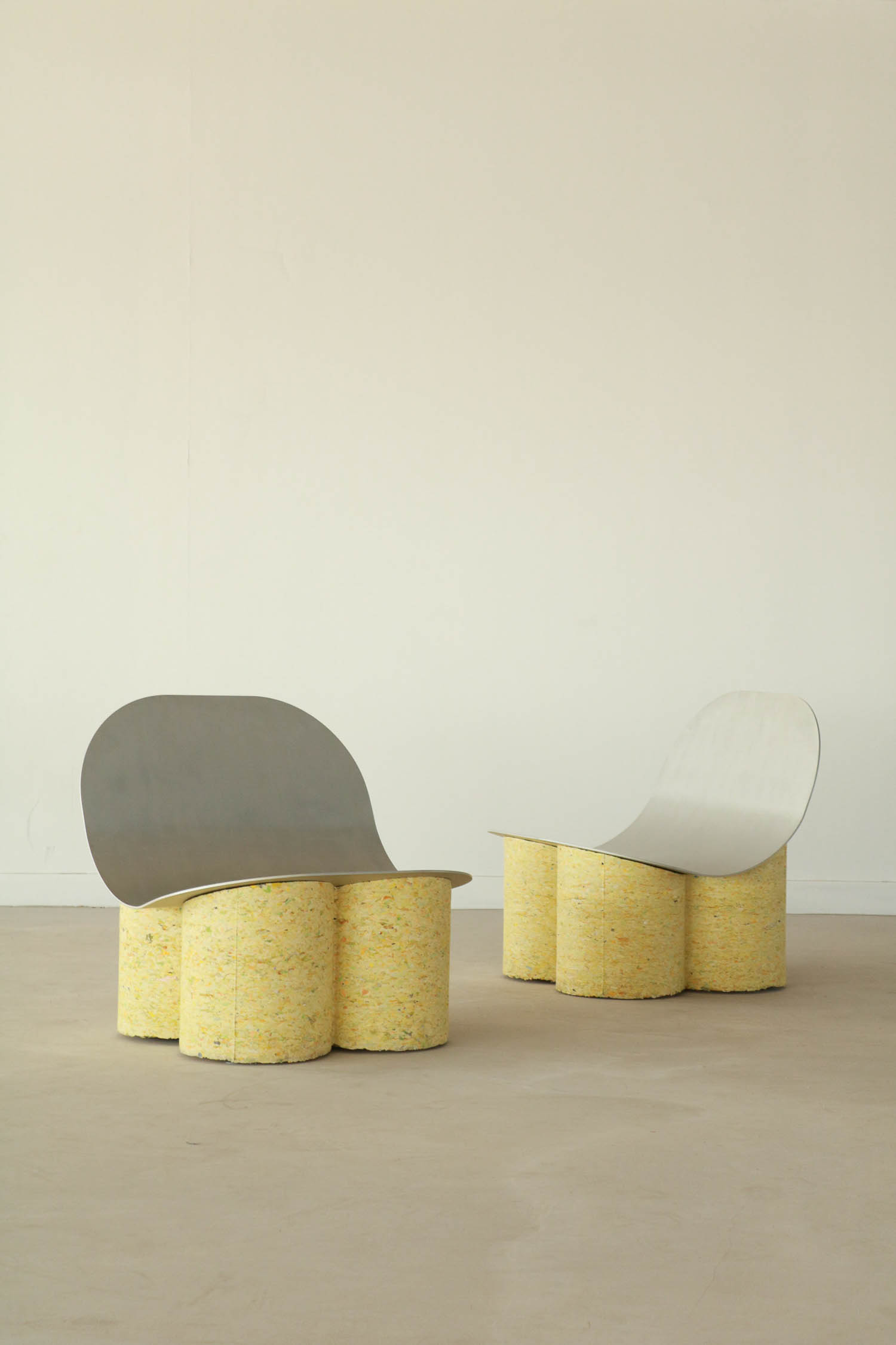 Two chairs with curved metal backrests and yellow foam bases shaped like clusters of cylinders.