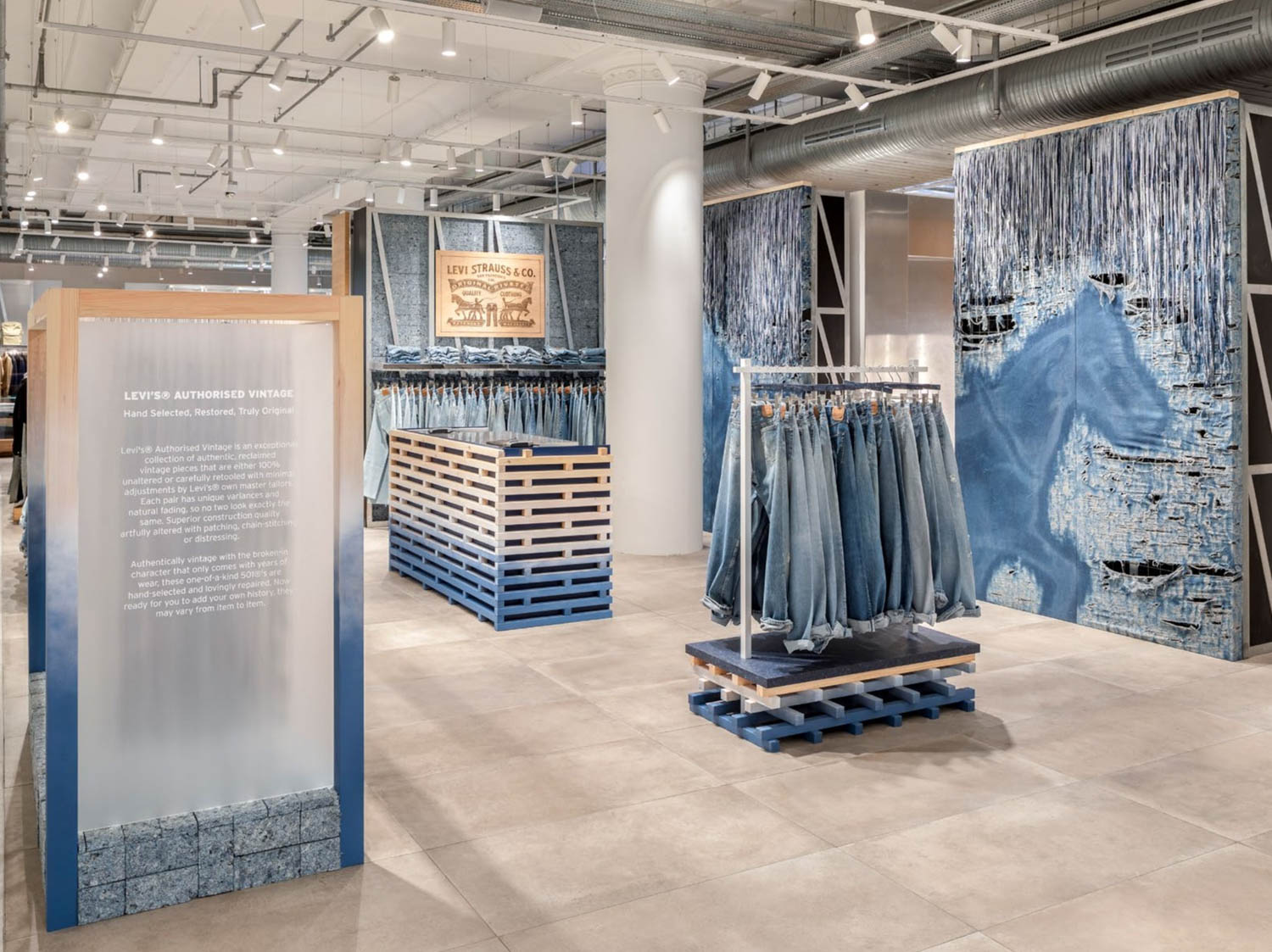Interior of a Levi’s store featuring a display sign about Authorised Vintage clothing, racks of jeans, and denim-themed wall art.