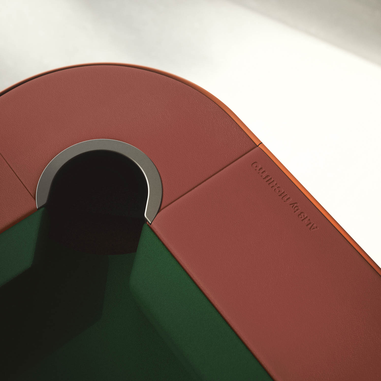 Close-up of a pool table corner with a red leather edge and a dark green playing surface, showing an embossed logo near the pocket.