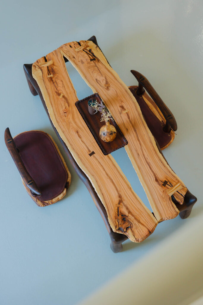 Low wooden coffee table with a live-edge top and two matching floor cushions, holding a small vase and bowl in the center.