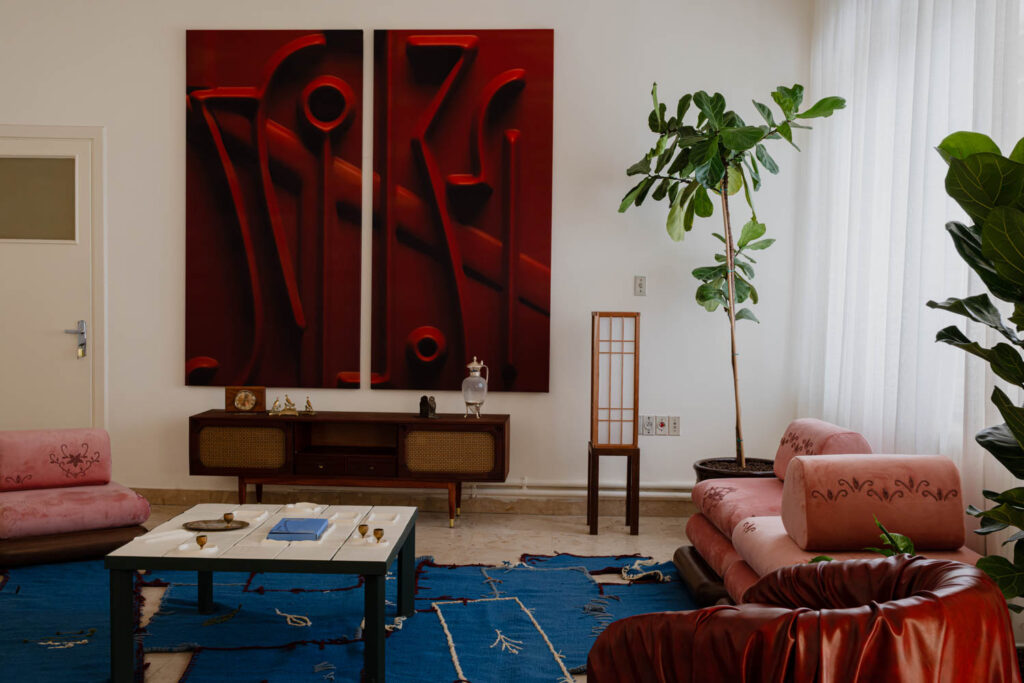Living room with pink sofas, a coffee table, a wooden media console, and two large red abstract paintings on the wall.