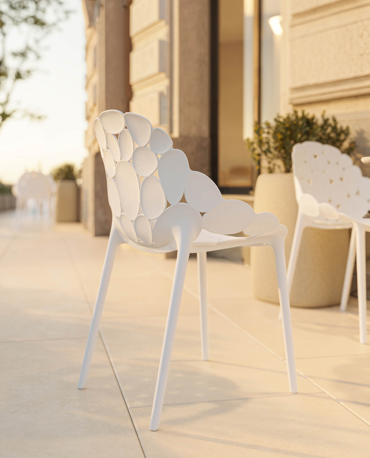 White outdoor chairs with a distinctive petal-patterned backrest on a patio.