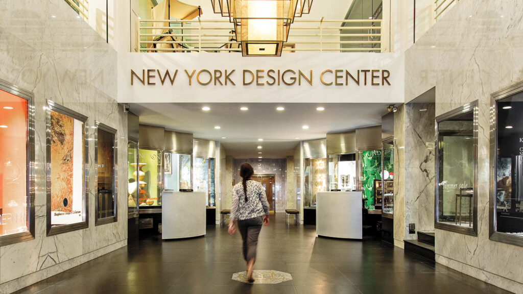 A person walks through the marble-clad lobby of the New York Design Center toward a central hallway.