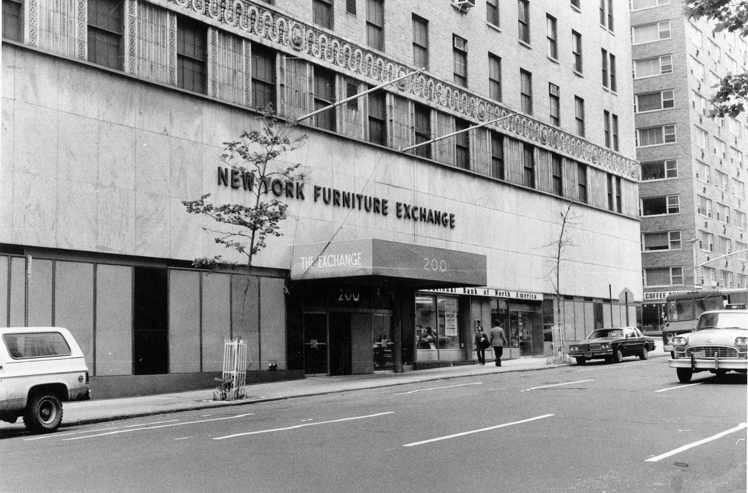 The New York Furniture Exchange building with cars parked on the street in front.
