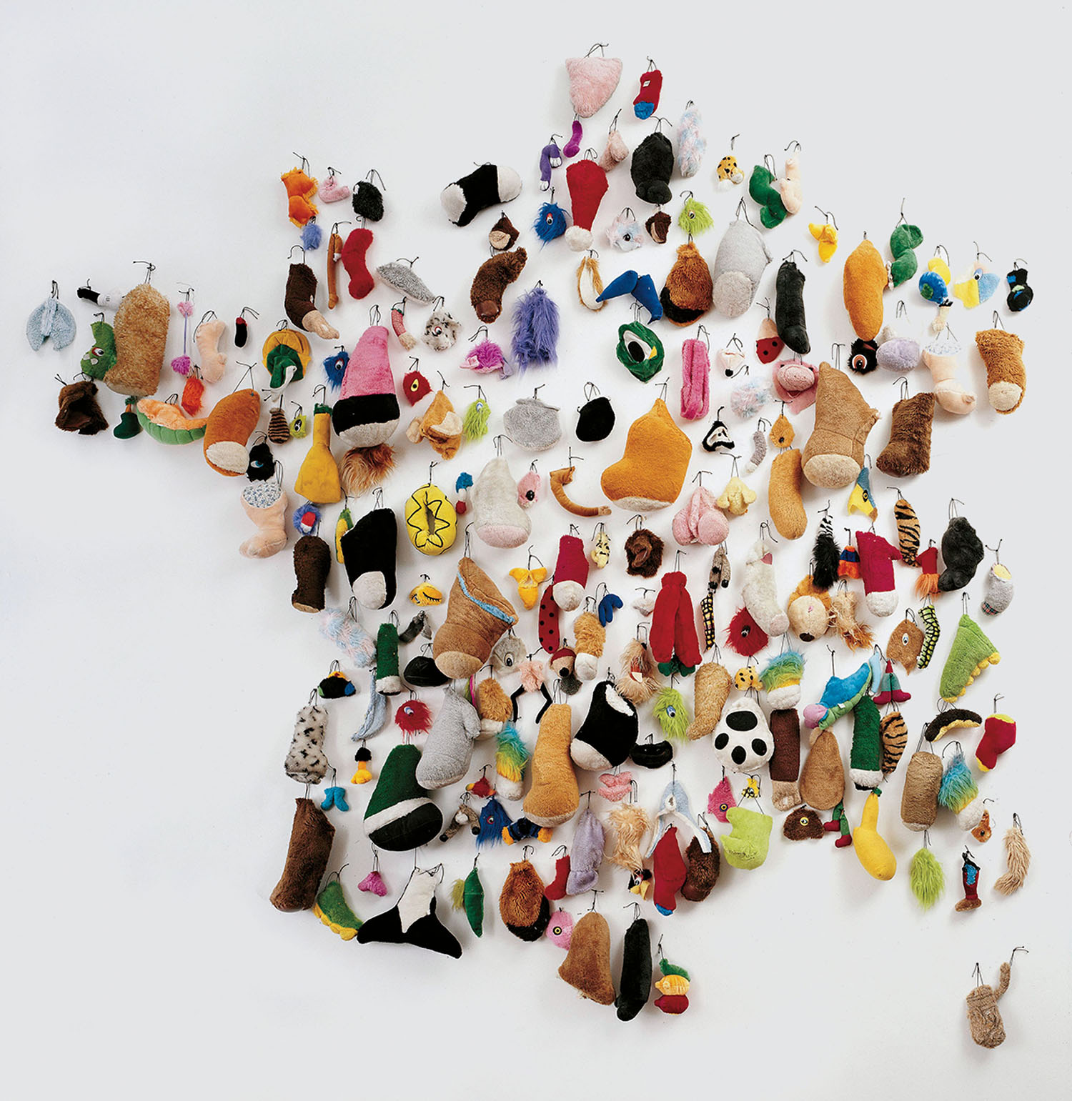 A collection of small, assorted fabric plush shapes and charms arranged on a white wall to form the map of France.