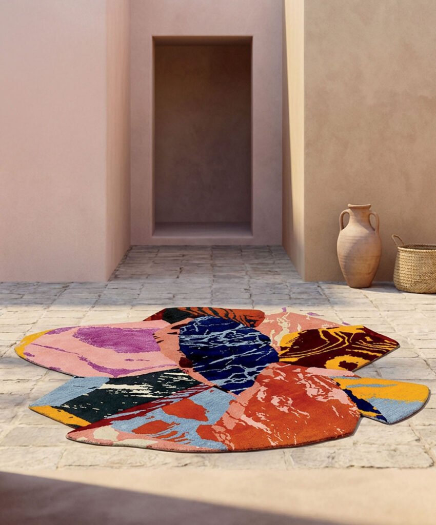 A flower-shaped area rug with a multicolored abstract pattern on a stone patio in front of a doorway.