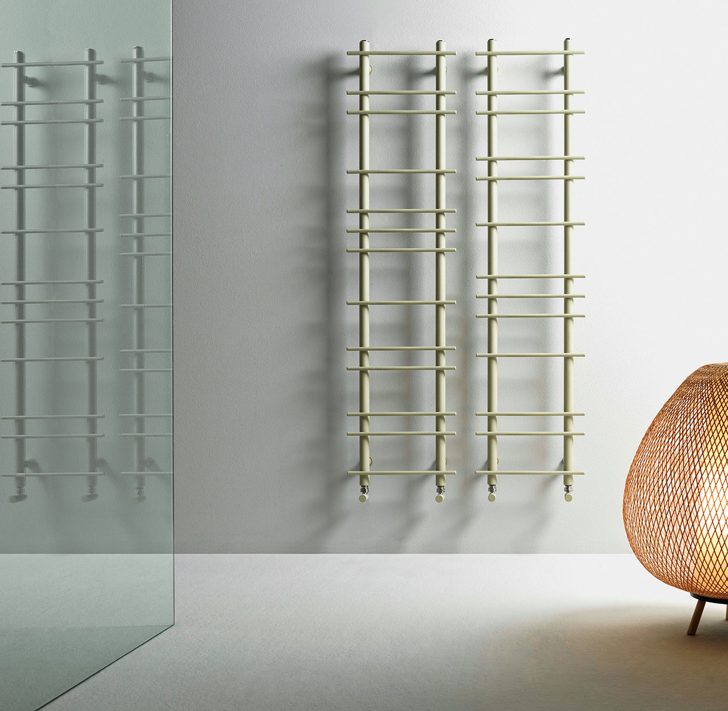 Two wall-mounted, light green ladder-style towel warmers hanging side by side in a bathroom.