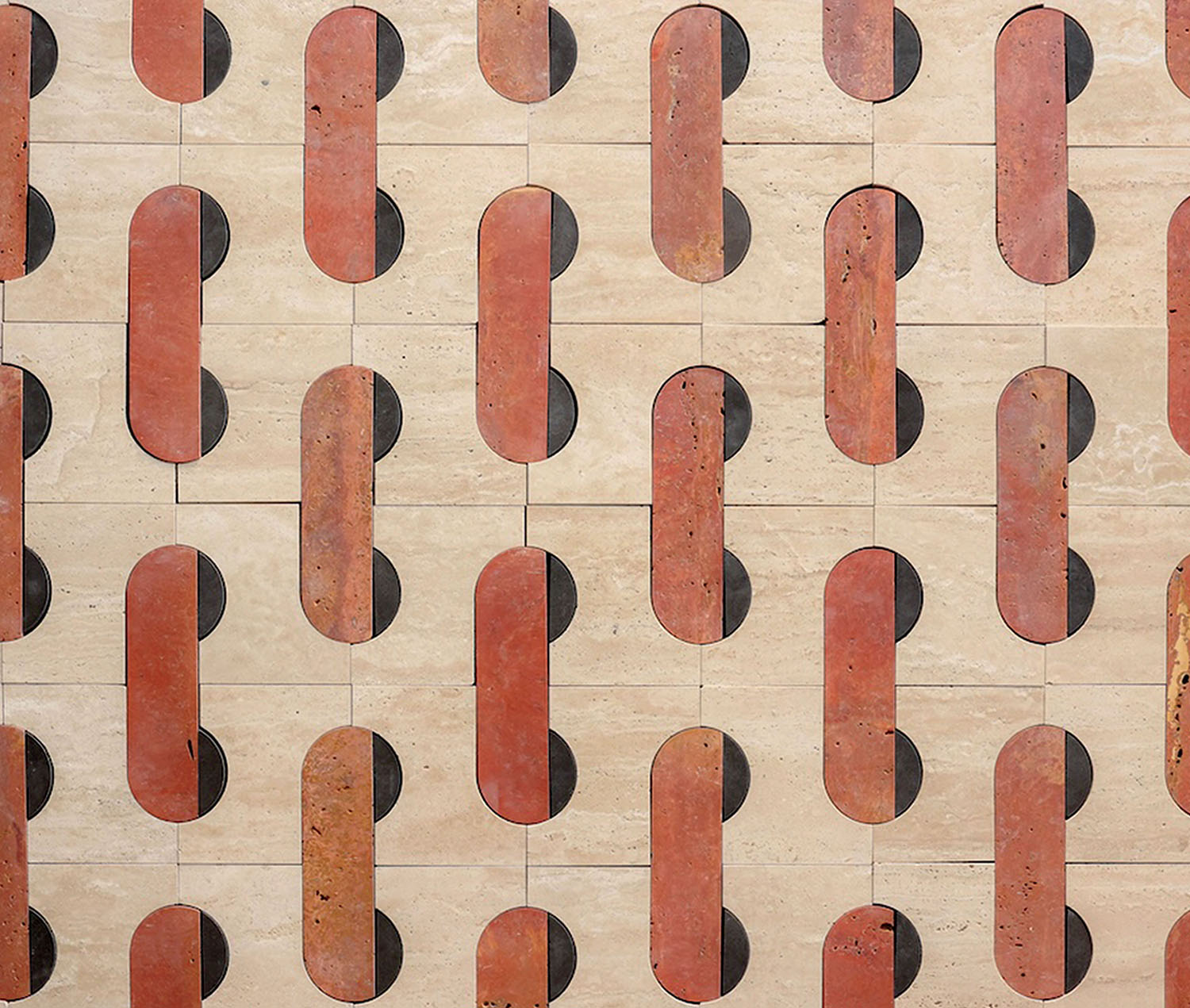 Pattern of repeating reddish-brown elongated shapes inlaid into light beige rectangular stone tiles.