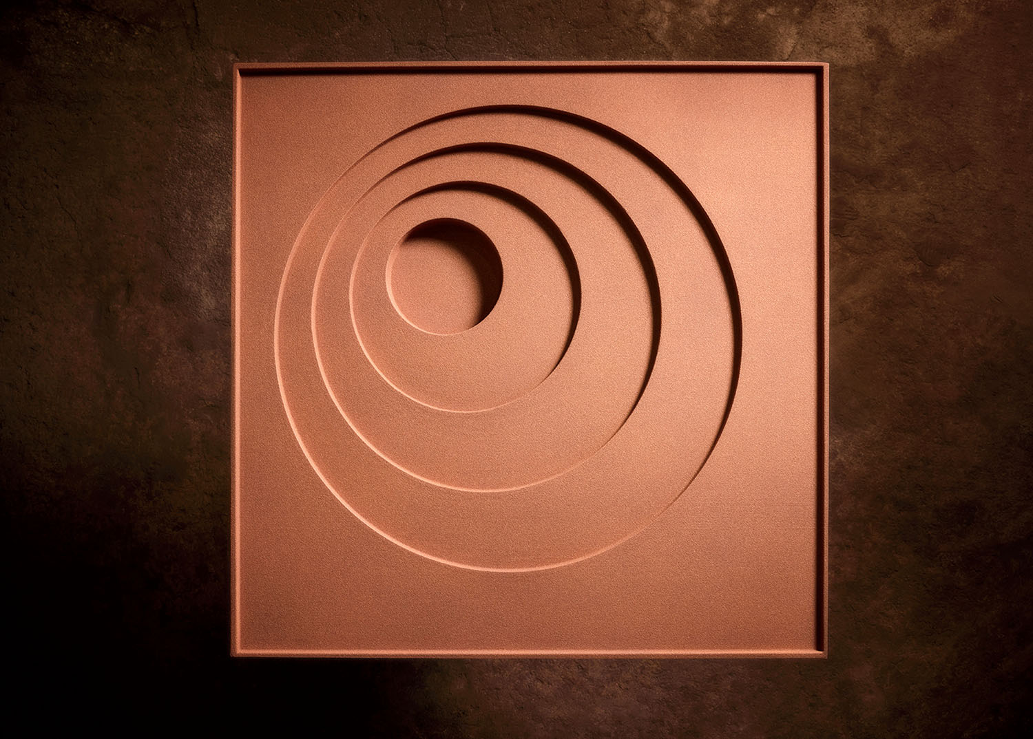A square panel with four concentric circular indentations of varying depths.